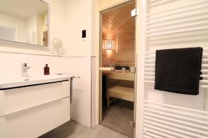 La salle de bains blanche est pourvue d'un lavabo et d'un miroir. dans l'établissement Dorumer Sielhuus 10 - Sauna und balkon, strandnah, à Dorum