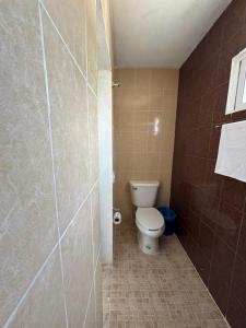 een badkamer met een toilet en een betegelde muur bij Posada Ceibamar Chichen Itzá in Pisté