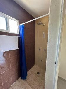 La salle de bains est pourvue d'une douche avec un rideau de douche bleu. dans l'établissement Posada Ceibamar Chichen Itzá, à Pisté