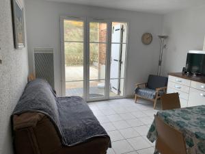 a living room with a bed and a sliding glass door at Maison à 50m de la Plage avec Parking Privatif - FR-1-482-140 in Fort-Mahon-Plage