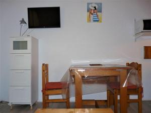uma mesa de jantar com cadeiras e uma televisão na parede em Appartement Bormes-les-Mimosas, 1 pièce, 2 personnes - FR-1-251-728 em Bormes-les-Mimosas