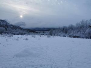 a field covered in snow with the sun in the background at Gîte de l'herboriste spa et vue sur la fjord in Sainte-Rose-du-Nord +34 photos