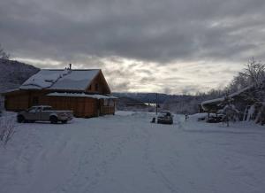 a snow covered house with a truck parked in front of it at Gîte de l'herboriste in Sainte-Rose-du-Nord