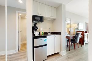 a kitchen with white cabinets and a dining room with a table at Bayside at Sandestin #6769 in Destin