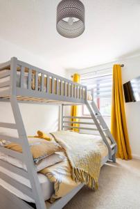 een wit stapelbed in een kamer met gele gordijnen bij Ochil View Holiday Let in Tullibody