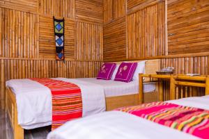 two beds in a room with wooden walls at Mai Chau Moment Spa & Resort in Mai Chau