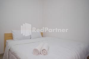 two towels sitting on top of a white bed at River House Mitra RedDoorz in Jatingaleh