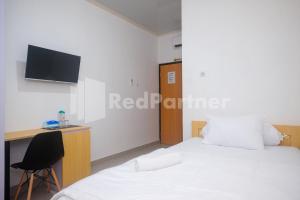a bedroom with two beds and a desk and a tv at River House Mitra RedDoorz in Jatingaleh
