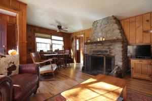 sala de estar con chimenea de piedra y mesa en Ahwahnee-be Vintage Cabin - Walk to town!, en Idyllwild