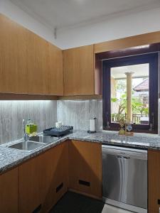 eine Küche mit Holzschränken, einem Waschbecken und einem Fenster in der Unterkunft Welcome to Serenity Villa. in Munggu