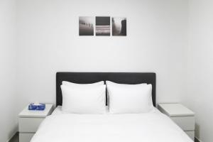 een slaapkamer met een wit bed met witte kussens bij Family Apartment #9 By Hashdera Eilat in Eilat