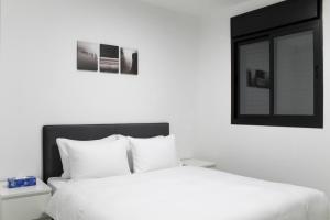 een slaapkamer met een bed met witte lakens en een raam bij Family Apartment #9 By Hashdera Eilat in Eilat