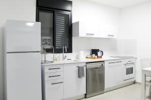 een keuken met witte kasten en een koelkast bij Family Apartment #9 By Hashdera Eilat in Eilat