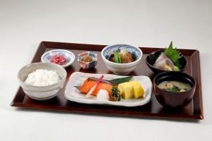 Richmond Hotel Kagoshima Tenmonkan في كاجوشيما: صينية طعام مع السوشي والأطباق الأخرى
