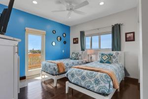 a blue bedroom with two beds and a window at The Marvelous 24 in Flagler Beach