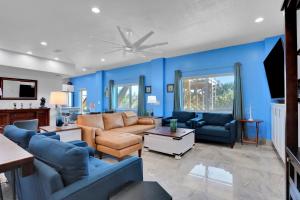 a living room with blue walls and a couch and chairs at Immaculate, modern stay steps to beach with amazing ocean views in Painters Hill