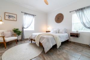 a white bedroom with a bed and a chair at SōLE Luxury Condo's in Cocoa Beach