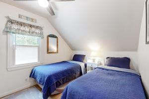 two beds in a attic room with blue blankets at Shoreline Serenade in Belmont