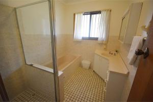 La salle de bains est pourvue d'une douche, d'une baignoire et d'un lavabo. dans l'établissement Echo Point Village, à Katoomba