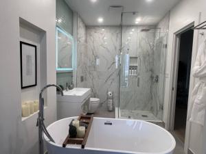 a white bathroom with a tub and a shower at Cozy 2 Bedroom with Parking in Toronto