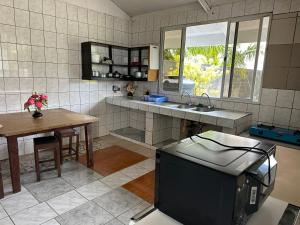 une cuisine avec une télévision et une table avec une table dans l'établissement Chambres bord de mer - raiatea, à Uturoa