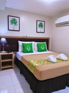 a hotel room with a large bed with green pillows at Airport Poddotel Inc. in Manila