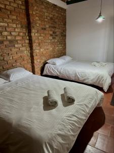 zwei Betten in einem Zimmer mit zwei Hüten darauf in der Unterkunft Villa San Carlos in Villa de Leyva