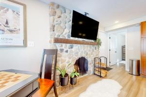 sala de estar con chimenea de piedra y TV en Wandering Creek Ski Chalet, en Stratton Mountain