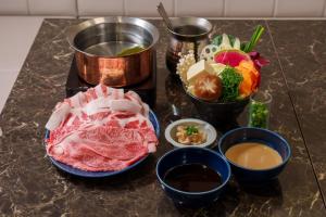 a table topped with meat and bowls of food at Doutonbori Crystal Exe in Osaka