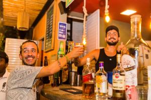 dos hombres parados en un bar sosteniendo una bebida en Bamboo Rio Hostel en Río de Janeiro