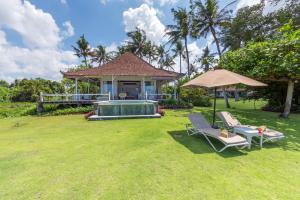a house with a pool and two chairs and an umbrella at Villa Sungai Laut in Canggu