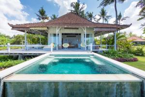 a swimming pool in front of a villa at Villa Sungai Laut in Canggu