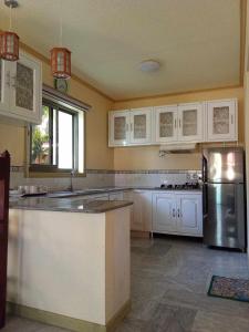 uma cozinha com armários brancos e um frigorífico de aço inoxidável em L&L Beach Resort em Pandan