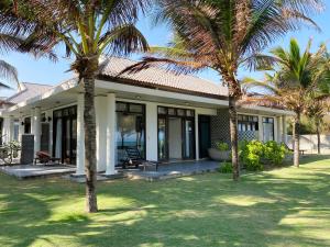 una casa con palmeras delante en Starlight Villa Beach Resort & Spa, en Phan Thiet