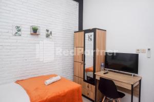 a bedroom with a bed and a desk with a television at Rumah Daun Timoho Yogyakarta RedPartner in Yogyakarta