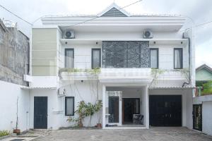 Una casa blanca con una puerta. en Rumah Daun Timoho Yogyakarta RedPartner, en Yogyakarta