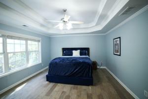 1 dormitorio azul con 1 cama y ventilador de techo en Big 5 Bdrm Private Hot Tub Pool Table Near Shops, en Loganville