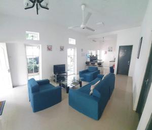 uma sala de estar com dois sofás azuis e uma televisão em Home From Home em Nugegoda