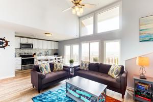a living room with two couches and a table at Oceanfront Oasis in Emerald Isle