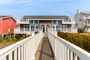 a house on the beach with a white fence at Oceanfront Oasis in Emerald Isle