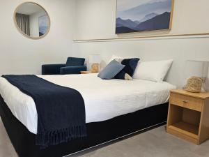 a bedroom with a bed and a chair and a mirror at Ballina Colonial Motel in Ballina