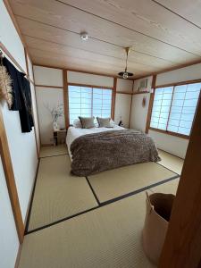 a bedroom with a bed in a room with windows at Shofusha Lodge Madarao Tangram in Madarao Kogen