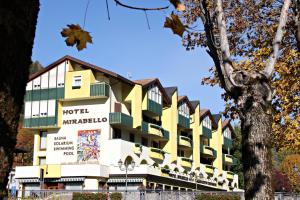 un hôtel avec un bâtiment jaune et blanc dans l'établissement Hotel Mirabello - Slow Hotel Benessere, à Fiera di Primiero