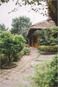 un bâtiment avec un toit de paille et quelques plantes et arbres dans l'établissement Trang An Mountain House, à Ninh Binh