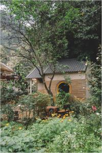 un jardin avec un hangar en bois et un arbre dans l'établissement Trang An Mountain House, à Ninh Binh
