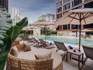 a patio with chairs and umbrellas and a pool at Nysa Hotel Bangkok Sukhumvit 11 in Bangkok