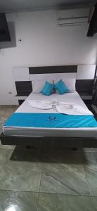 - un lit avec des draps bleus et blancs et des oreillers bleus dans l'établissement Hotel Sol Del LLano, à Villavicencio