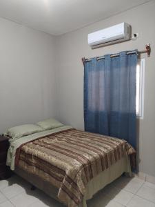 a bedroom with a bed with a blue curtain at Posadas Mateo in La Lima