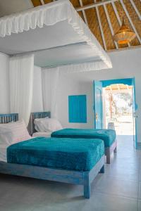 two beds in a bedroom with blue and white at Ocean Paradise Bali in Buleleng