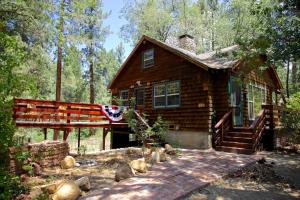 eine Blockhütte im Wald mit einer Flagge in der Unterkunft Ahwahnee-be Vintage Cabin - Walk to town! in Idyllwild